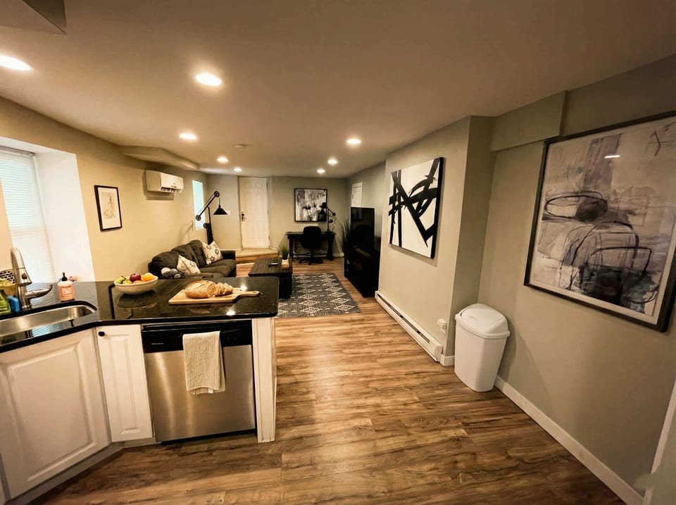 Open kitchen and living area with island, sofa seating, TV, and wall art.