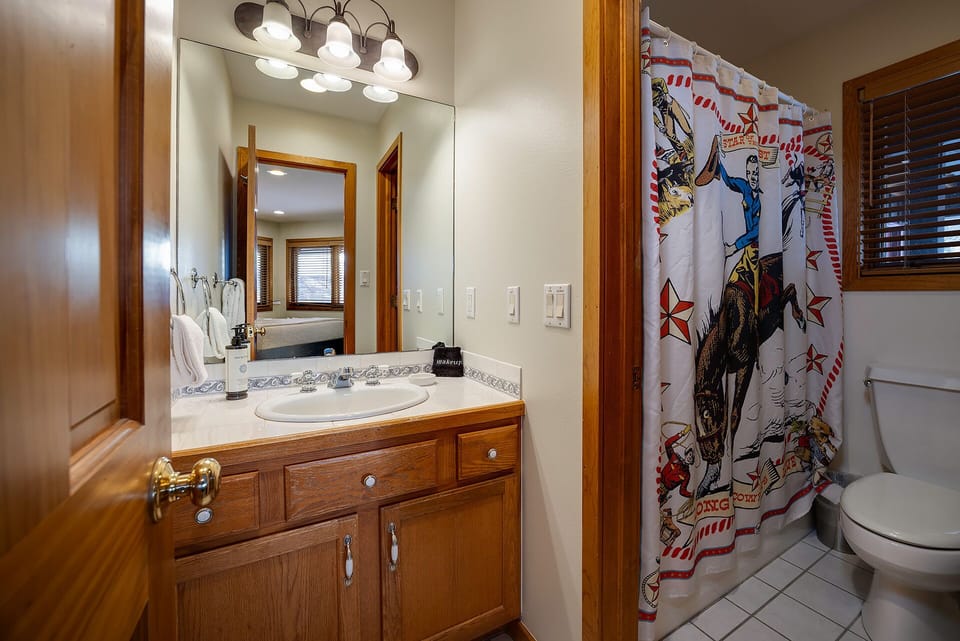 Freshen up in your private bathroom with its warm wood tones, spacious vanity, and playful Western-themed shower curtain that adds character to your stay.