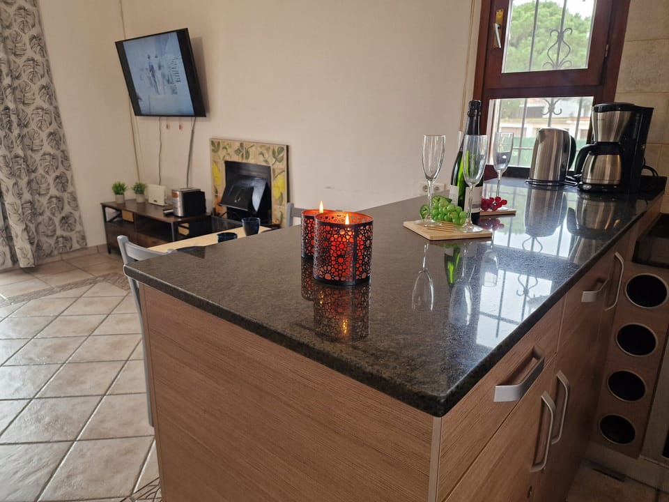 Practical view from the second entrance directly into the modern kitchen of House Noella with the open fireplace in the background.