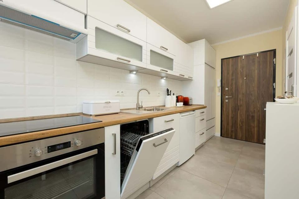 A closer look at the kitchen counter featuring a toaster, kettle, and neatly arranged cups and utensils.