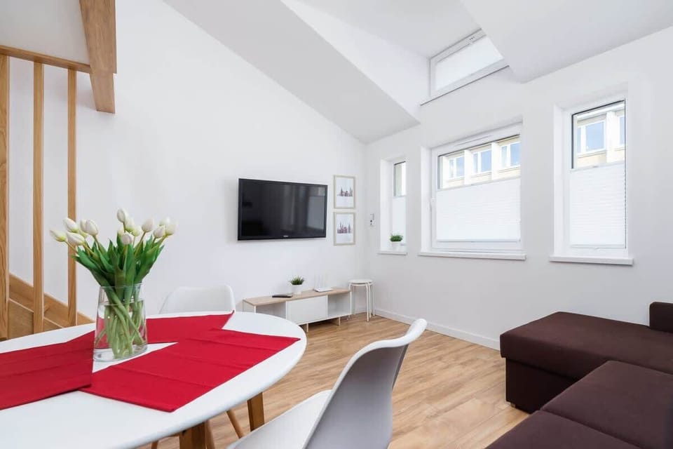 Bright and spacious studio interior featuring a comfortable sofa, dining table, and stylish red kitchen backsplash.