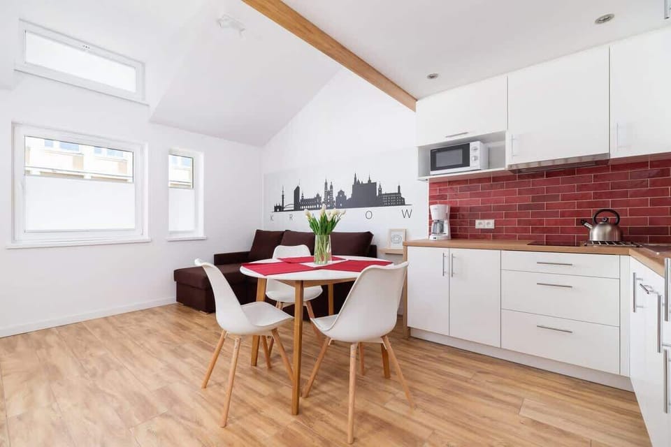 Fully equipped kitchen with modern appliances, red backsplash tiles, and a dining table for two.