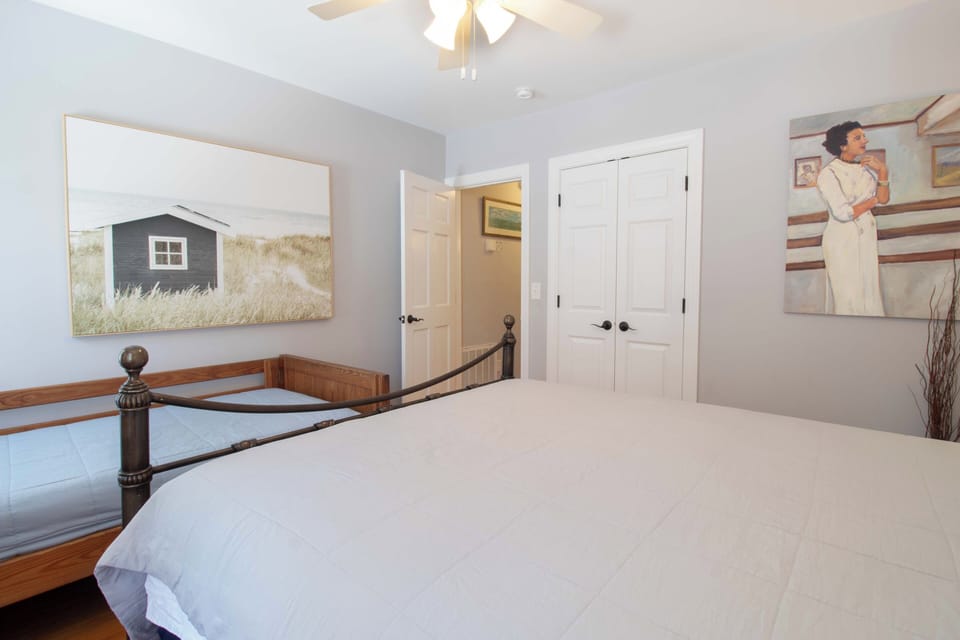Step into your serene bedroom retreat with crisp white linens and coastal-inspired artwork inviting peaceful rest after your beach adventures.