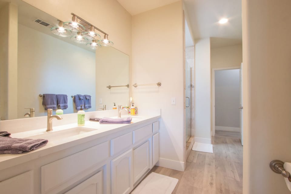 This bathroom offers a long double vanity and a glass-enclosed shower.