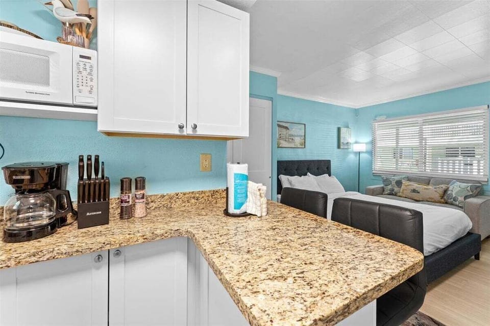 Fully equipped kitchenette with granite counters, white appliances, microwave, and bar seating for two — everything you need for a home-cooked meal.