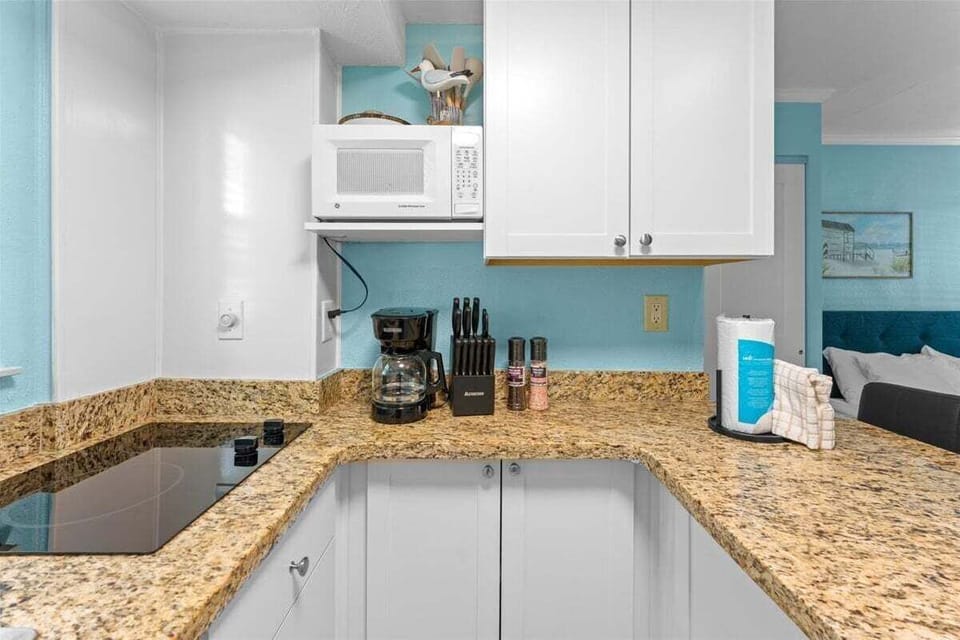 Fully equipped kitchenette with granite counters, white appliances, microwave, and bar seating for two — everything you need for a home-cooked meal.
