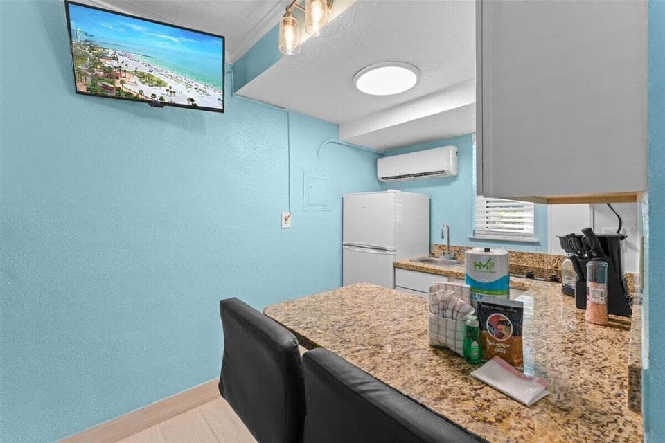 Fully equipped kitchenette with granite counters, white appliances, microwave, and bar seating for two — everything you need for a home-cooked meal.