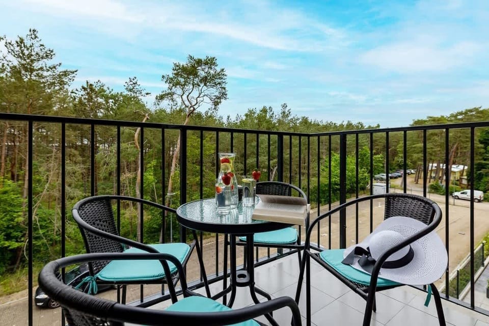 A balcony with a small table and chairs overlooking a forested area.