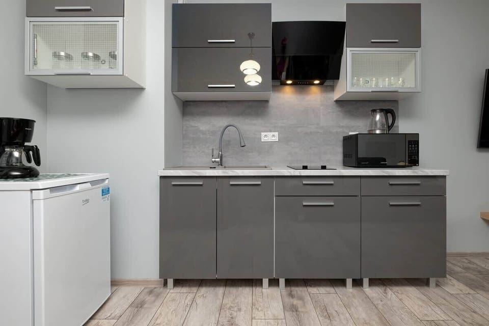 A modern kitchen area with built-in cabinets, stove, and small refrigerator.