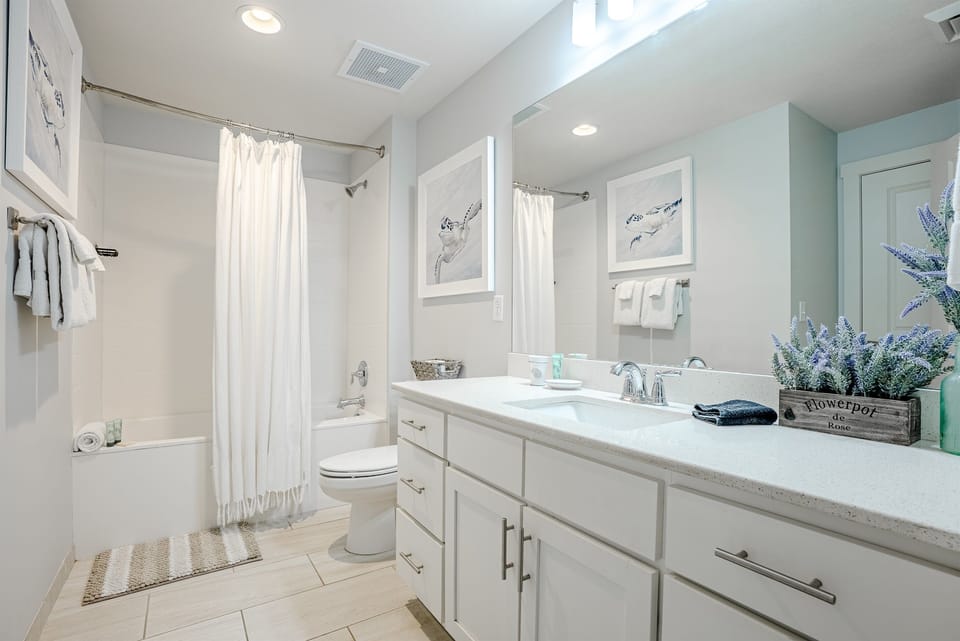 The guest bathroom is one of those “oh good, this is nice” moments. Bright, clean, and easy to move around in—double sinks for kids who somehow need everything at the same time, and a full tub/shower that makes bath time simple after a sandy beach day.