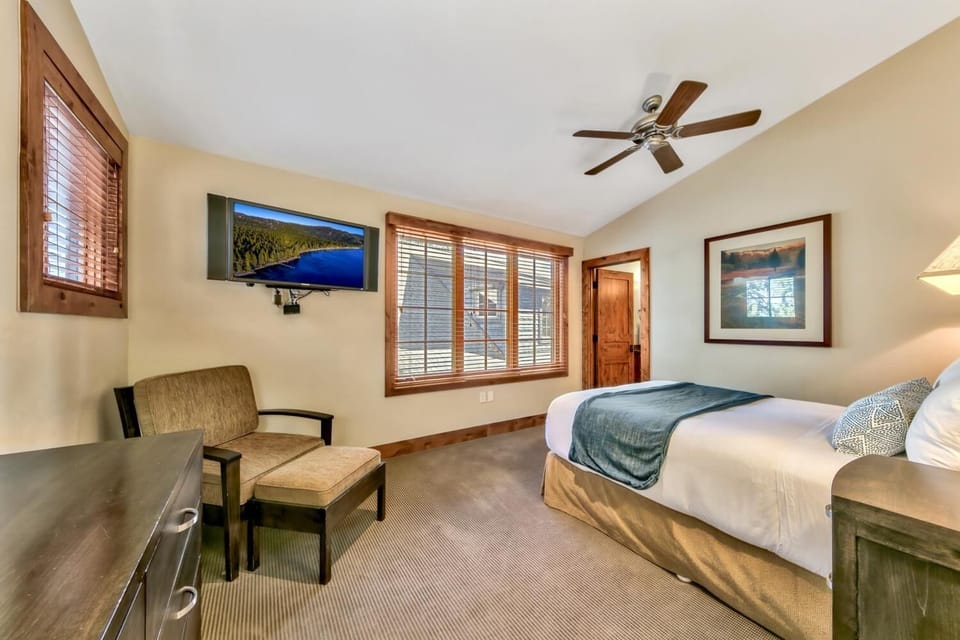 Unwind in your peaceful bedroom with mountain views on TV, cozy seating, and warm wood accents creating the perfect retreat.