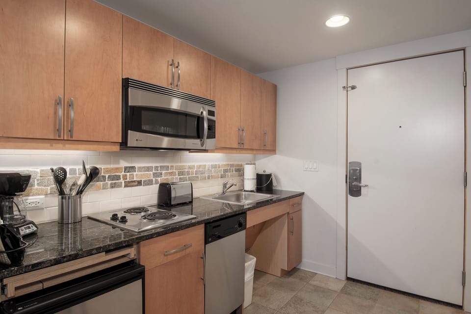 Your fully equipped kitchen features sleek granite counters, stainless appliances, and warm wood cabinets—perfect for preparing meals during your stay.