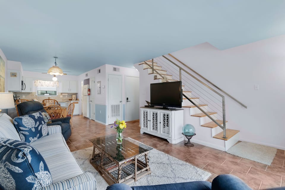 Discover this well-appointed living room, offering a functional open layout, a stylish entertainment console, and convenient access to the upstairs level.