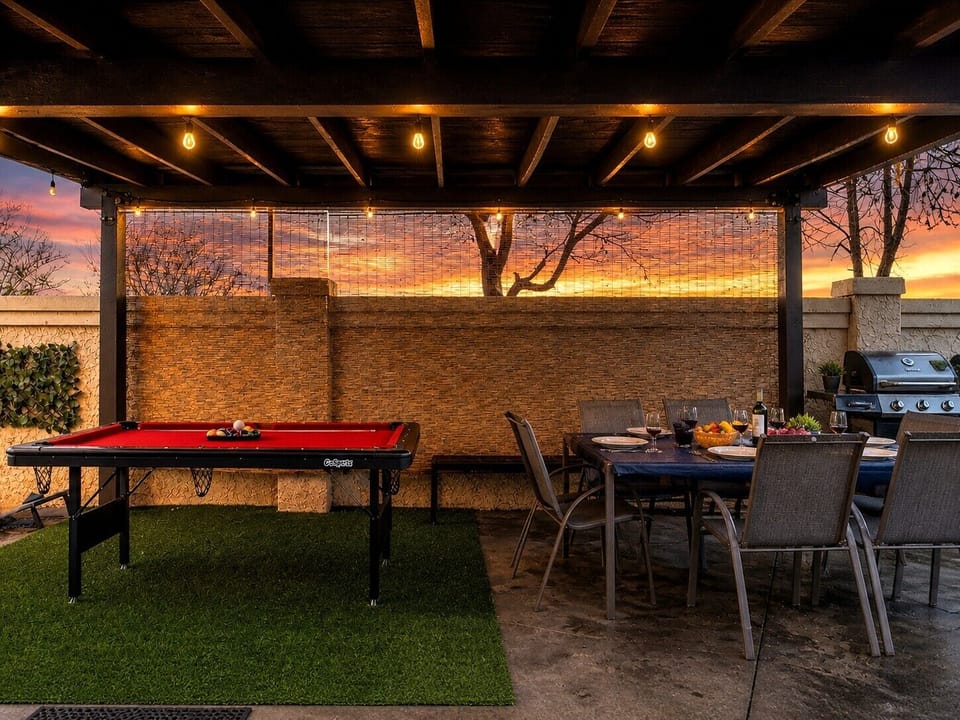 Pool table and dining table under a covered patio, adjacent to the grill—perfect for group gatherings