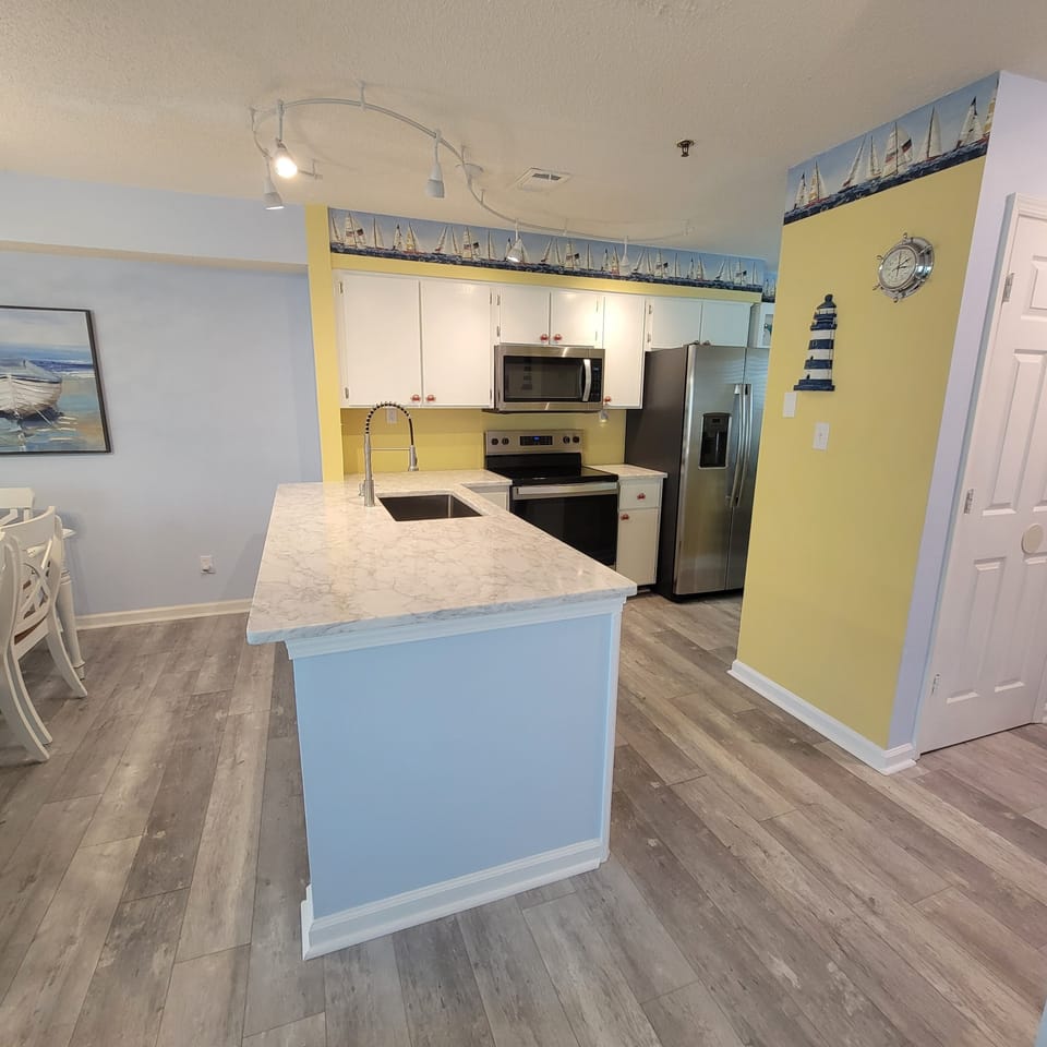 Kitchen with stainless steel appliances. Open floor plan dining and living area.