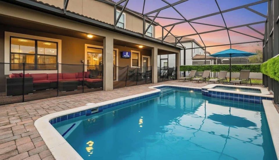 Inviting patio with pool, hot tub, lounge chairs, and a cozy red sectional, perfect for relaxation.