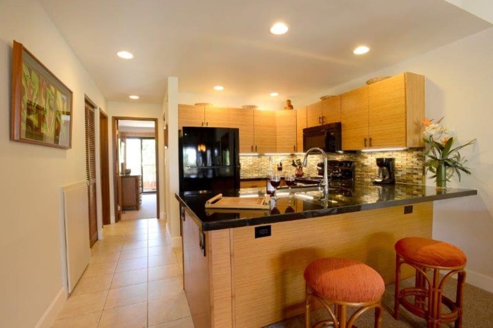 Your sleek kitchen features rich granite countertops, warm wood cabinetry, and a breakfast bar where you can start your mornings with coffee and conversation.