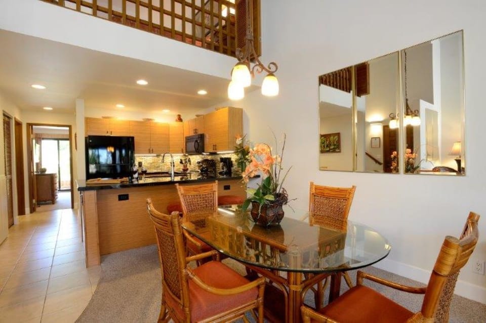 A bright open-plan living space with high ceilings, a full kitchen with modern appliances, and a glass dining table for shared meals—perfectly designed for your island getaway.