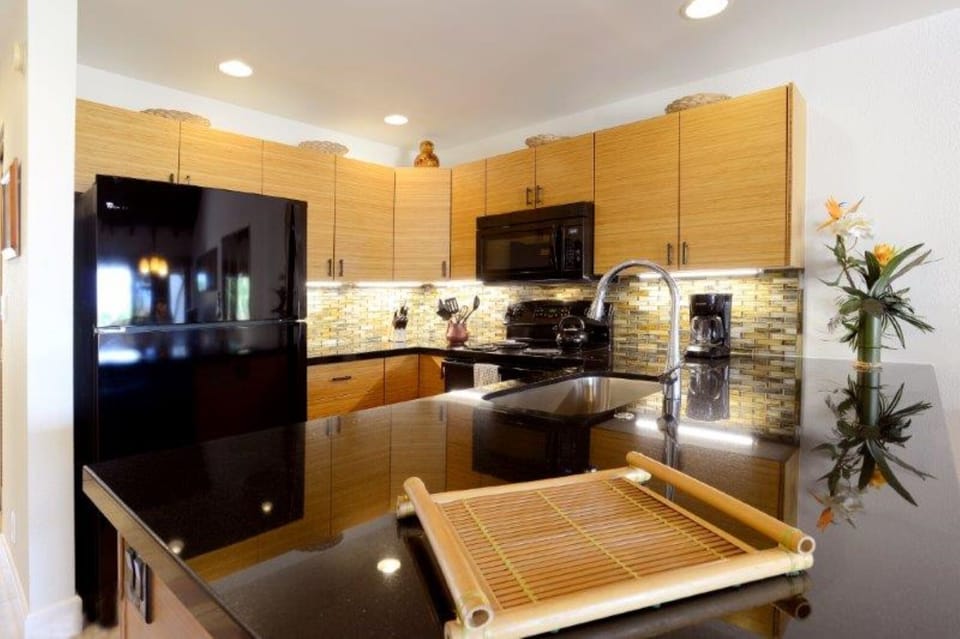 Your fully equipped kitchen features sleek black appliances, warm wood cabinetry, and modern tile backsplash—perfect for preparing meals during your stay.
