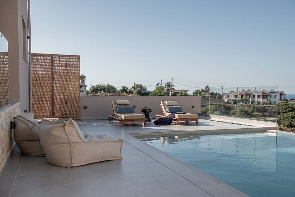Peaceful poolside setting with sunbeds and poufs.