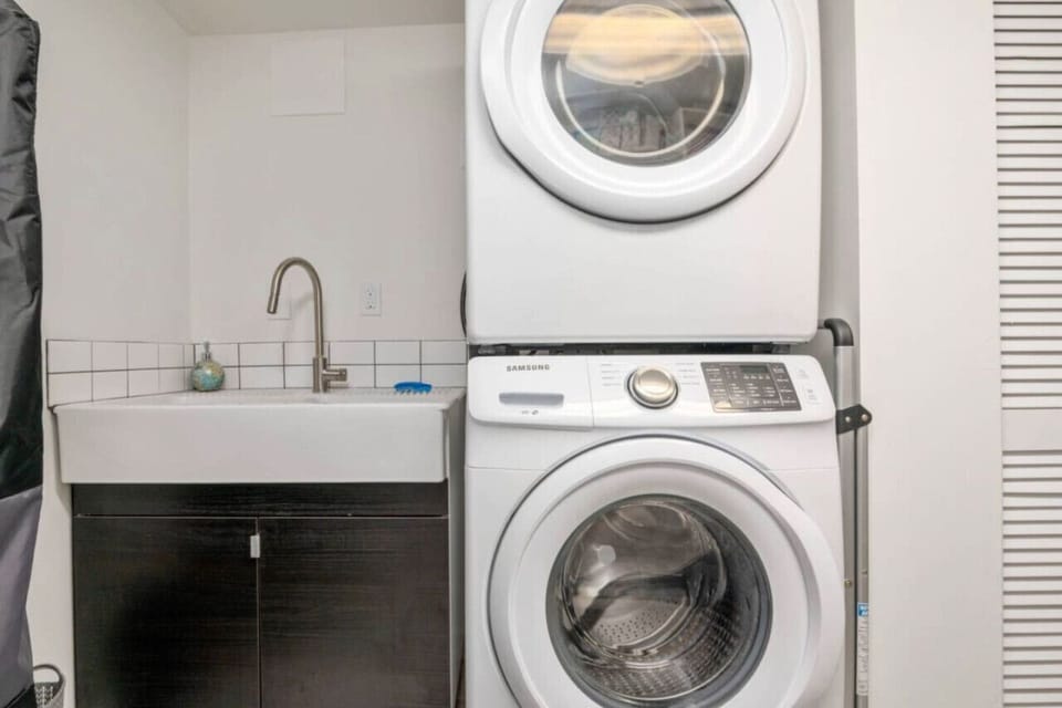 Full laundry room with utility sink, washer, dryer, and drying rack.