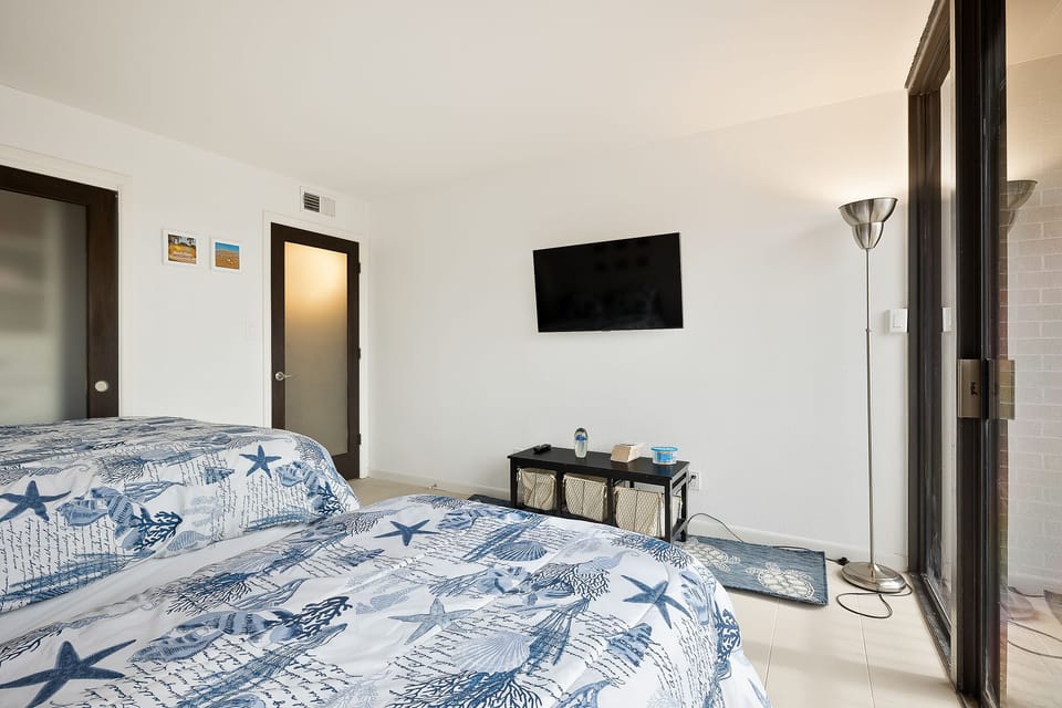 Bright guest room with twin and queen bed, TV and balcony access