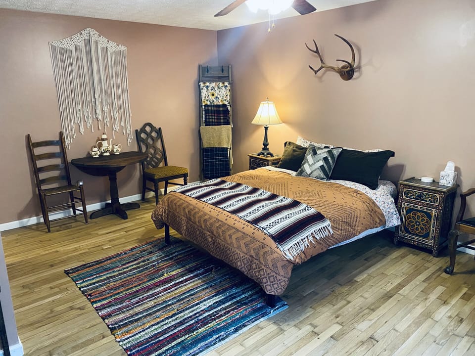 Main bedroom with queen bed, electric fireplace, desk, and, day bed.
