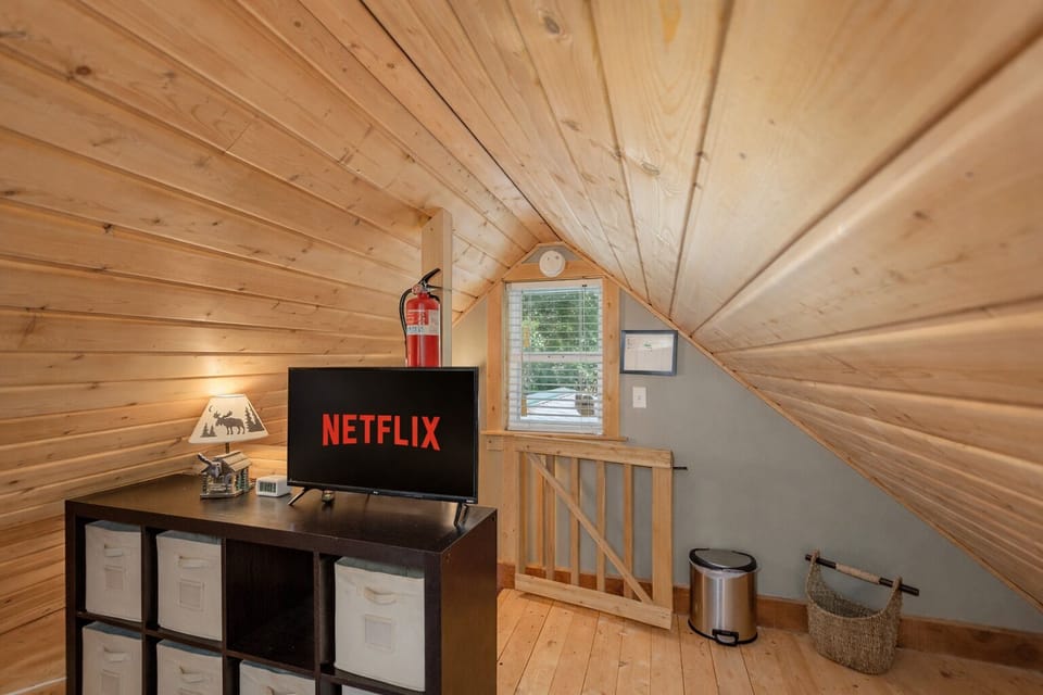 Your cozy loft retreat awaits with warm wood paneling, a smart TV for movie nights, and charming storage cubbies to keep your space organized.