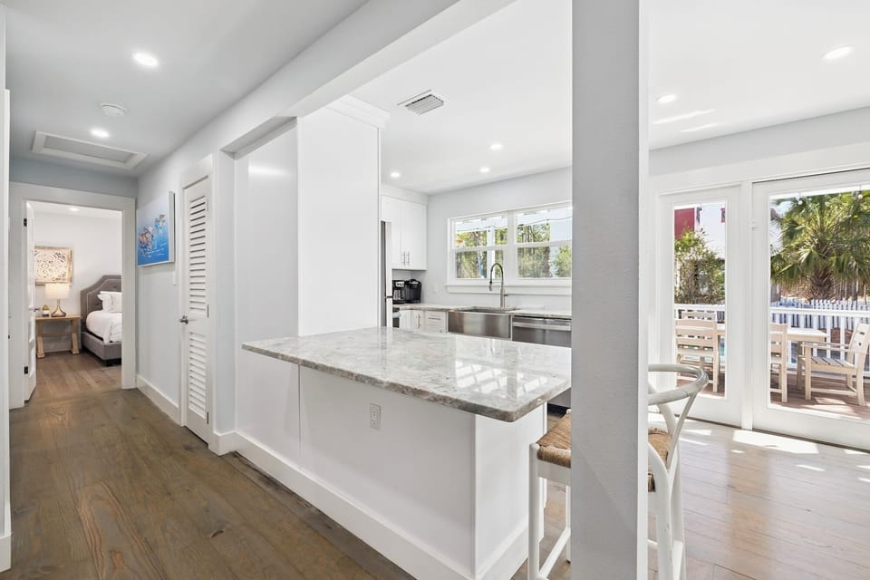 Cook with ease in your sleek white kitchen featuring marble countertops, modern appliances, and bright natural light streaming in.