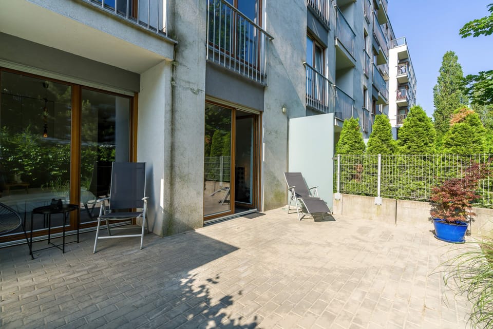 A view of the terrace outside the apartment surrounded by lush plants and outdoor furniture.