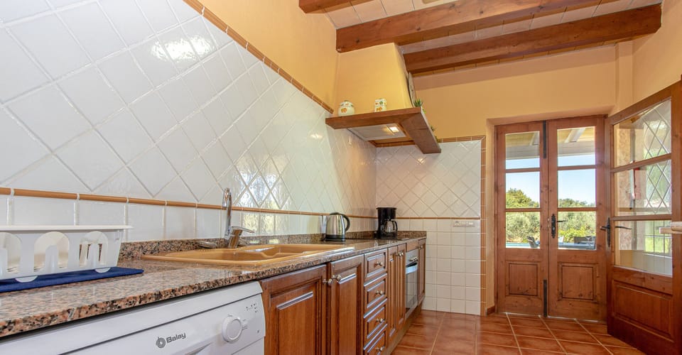 Rustic kitchen equipped with appliances, granite countertop and access to the garden terrace.