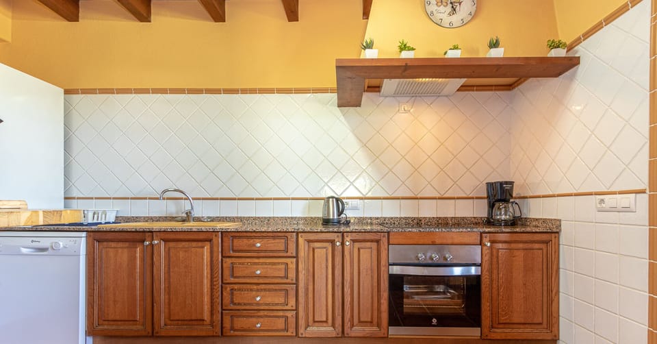 Rustic kitchen with wooden cabinets, modern appliances and granite countertop.