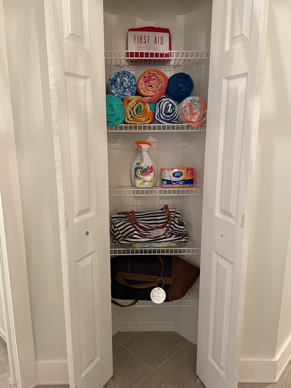 Linen closet with beach towels, first aid kit, soft sided cooler and beach bag