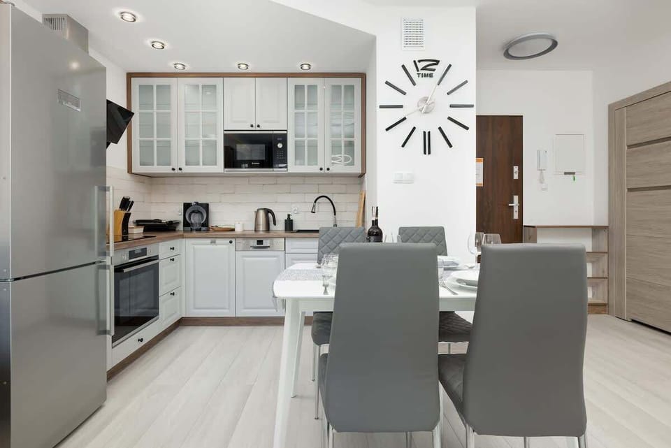 The dining and living area with modern furniture, including a white dining table and a fully equipped kitchen in the background.