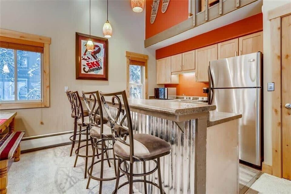 Fully-stocked kitchen with four bar stools next to the dining area