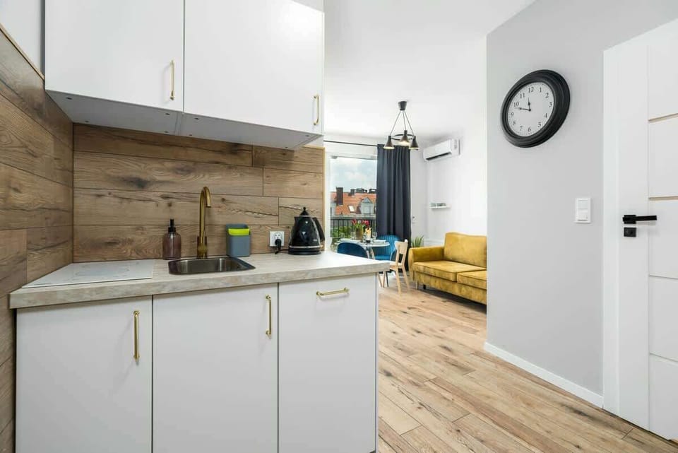 A compact, modern kitchen featuring white cabinets, wooden countertops, and essential appliances.