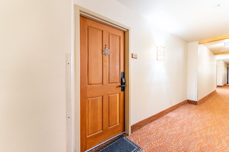 Step into your welcoming retreat through this elegant wooden door, where warm carpeted hallways lead to your comfortable home away from home.