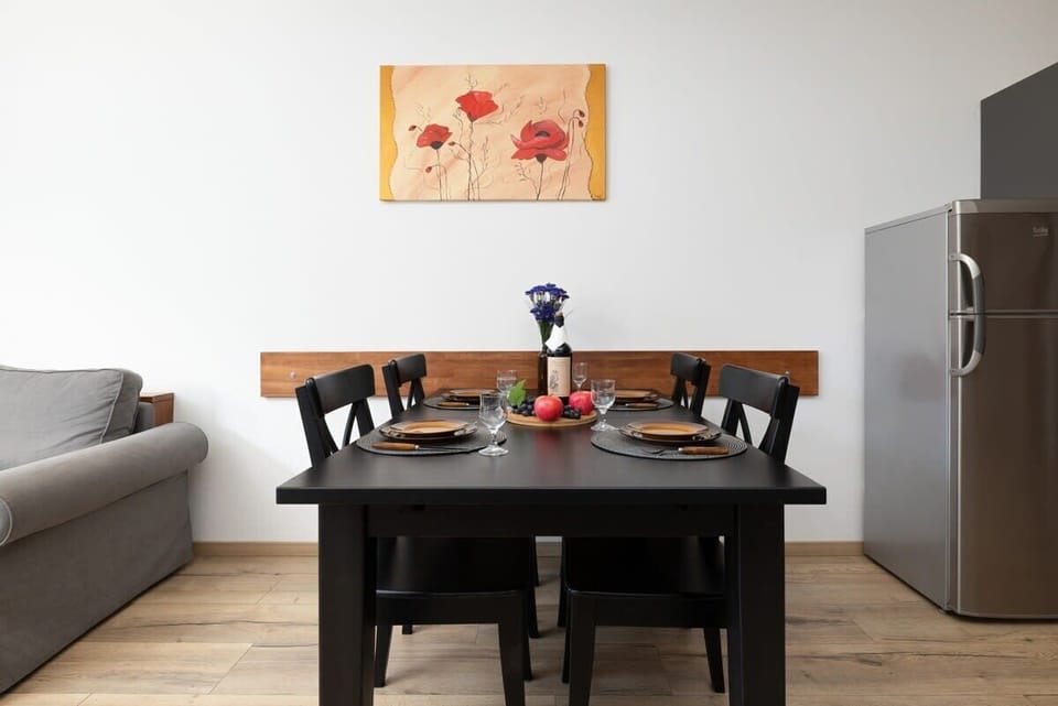 A bright and modern living room with a gray sectional sofa, a dining table with chairs, and minimalistic decor.