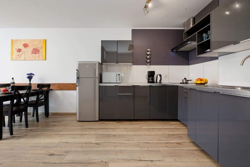 A well-equipped kitchen with modern gray cabinets, stainless steel appliances, and a wooden floor for a sleek finish.