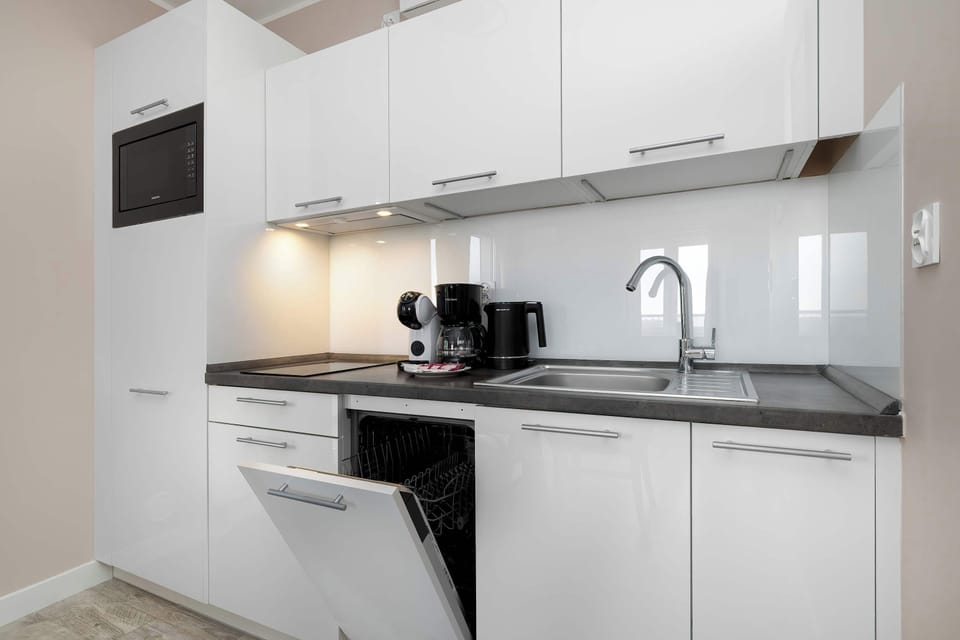 A sleek kitchen with white cabinetry, built-in appliances, and minimalist design.