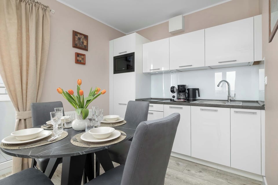 A dining area with a table set for a meal, placed next to a modern kitchenette.