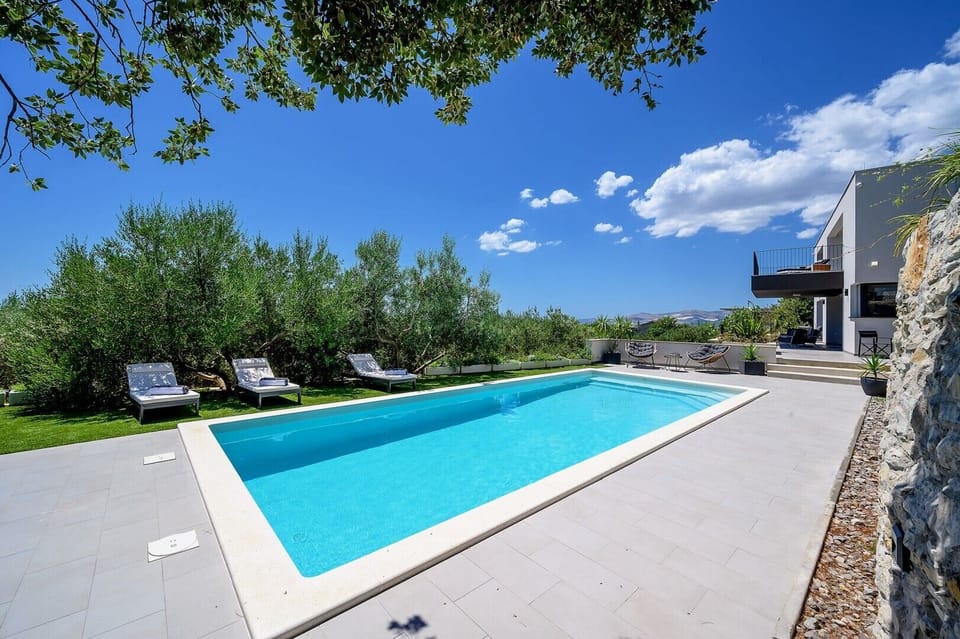 Pool area with deck chairs in the shade in the luxury family villa in Split