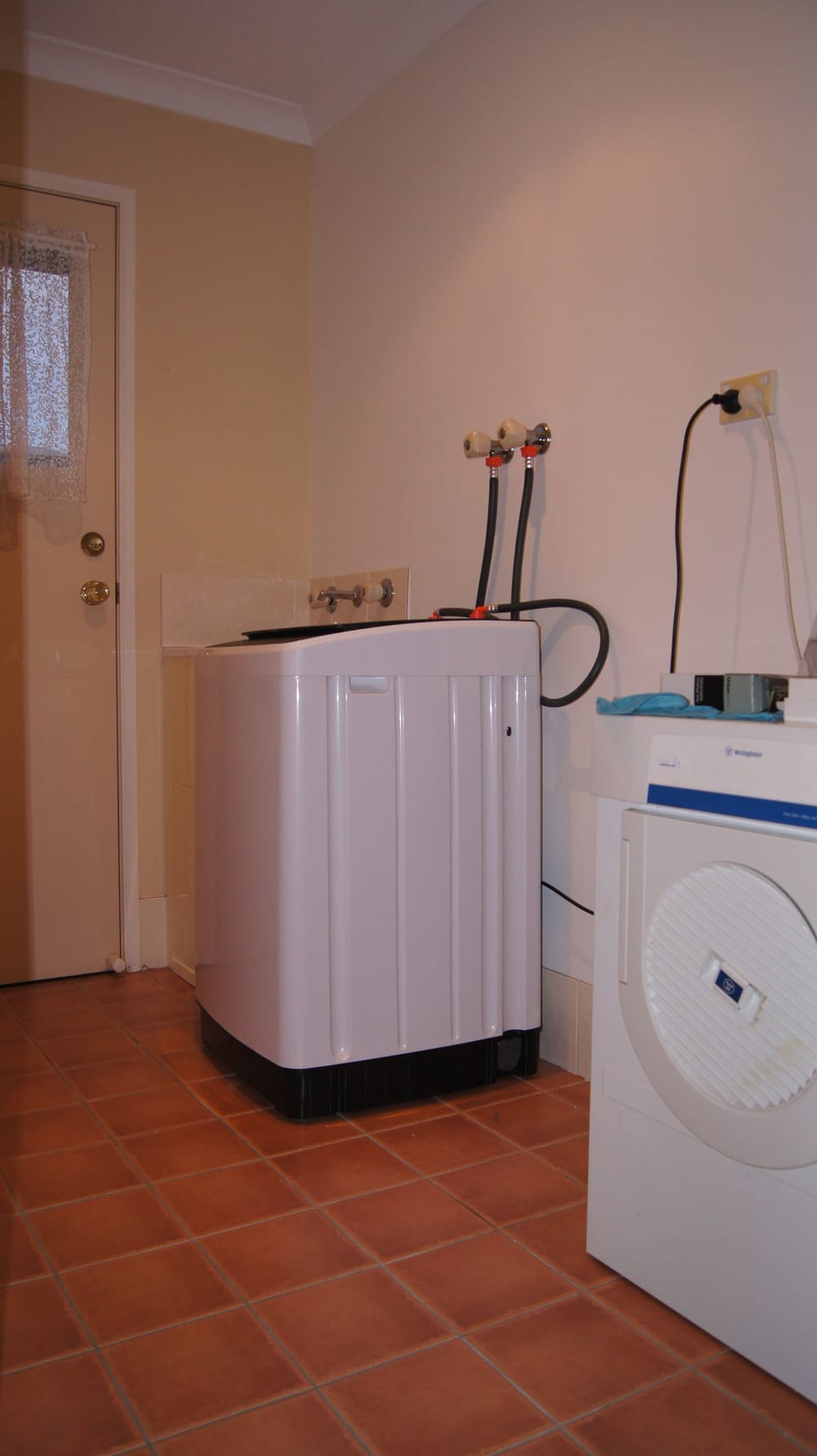 Laundry with top-loader washing machine, and dryer. Washing line thru door.