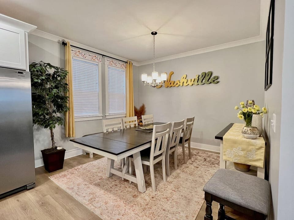 Dining area with Nashville wood sign, dark dining table, gray chairs, and large plant
