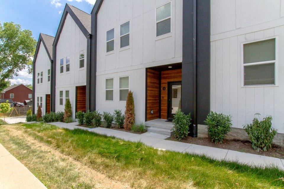 Exterior showing two townhouse units with gray and white facade and green lawn