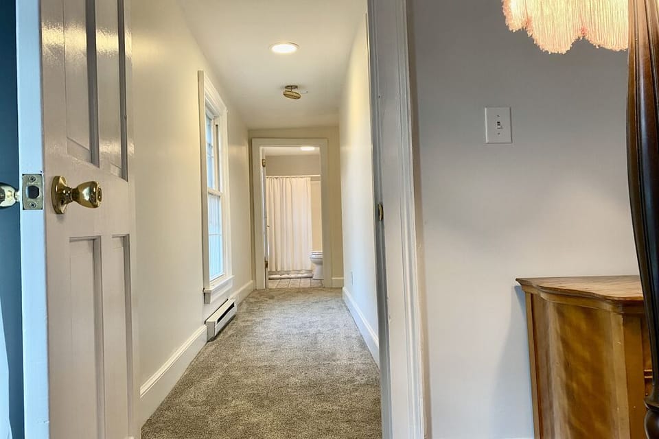 View from primary bedroom to full bath at end of hall