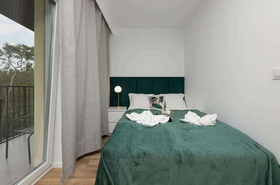 Comfortable master bedroom with a large double bed, rich emerald tones, and panoramic window views.