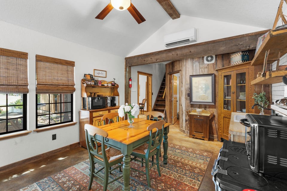 Share meals in a bright dining space with rustic beams, large windows, and farmhouse character.