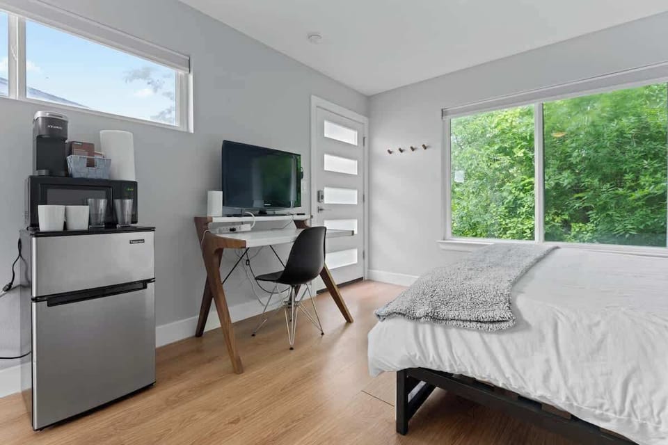 This cozy Austin, Florida retreat features a queen bed, smart TV, workspace & coffee machine, with a large window framing peaceful views capturing the charm of Austin, Florida in Austin, Florida.
