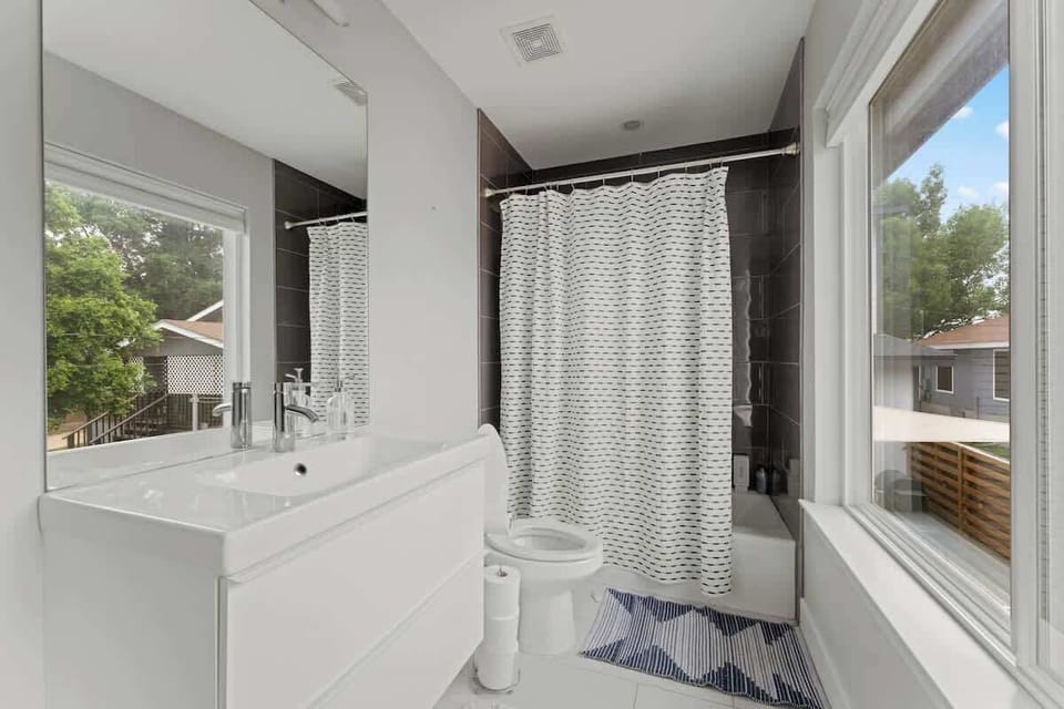 Bright, modern bathroom in this Austin, Florida retreat with sleek fixtures, a relaxing bathtub & tranquil views perfect for refreshing & recharging in Austin, Florida, at the heart of Austin, Florida living.